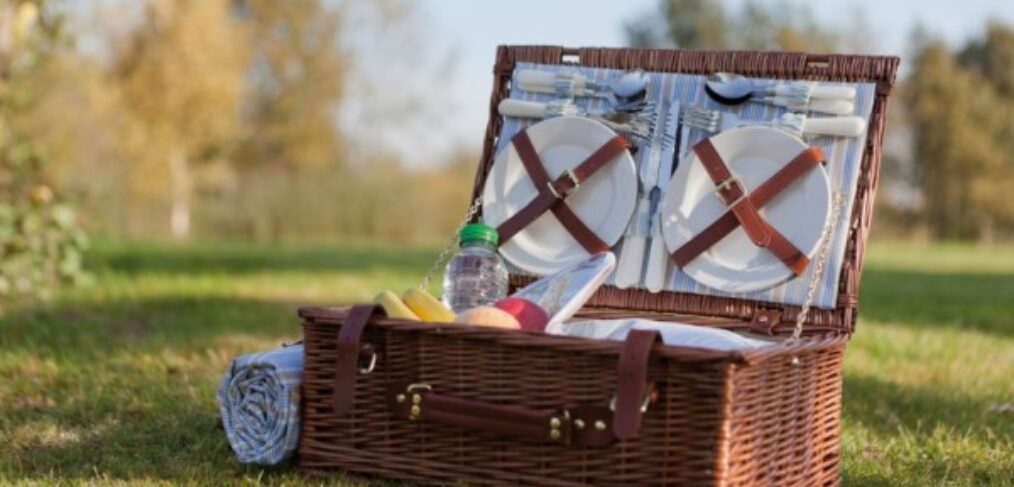 Rieten picknickmand met materiaal in. In een mooi veld tijdens goed weer.
