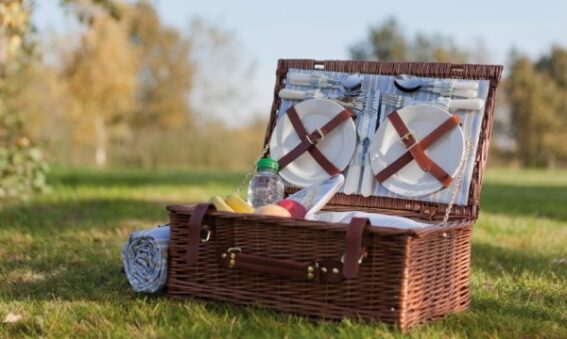 Rieten picknickmand met materiaal in. In een mooi veld tijdens goed weer.
